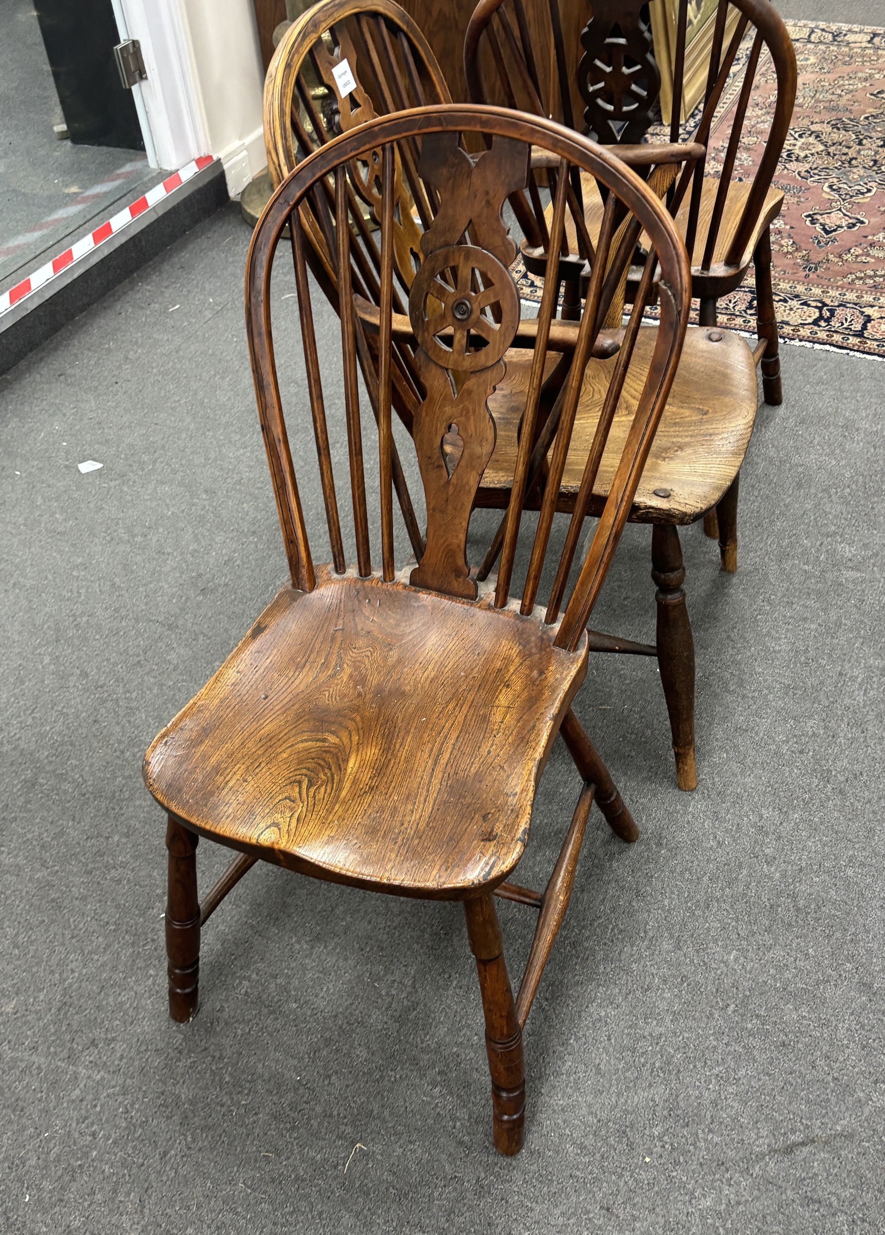 A set of three mid 19th century elm and ash wheel back dining chairs, one with arms